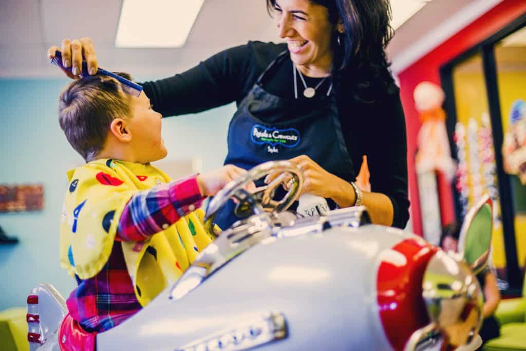 Stylist and client interacting at Pigtails & Crewcuts children's haircut franchise