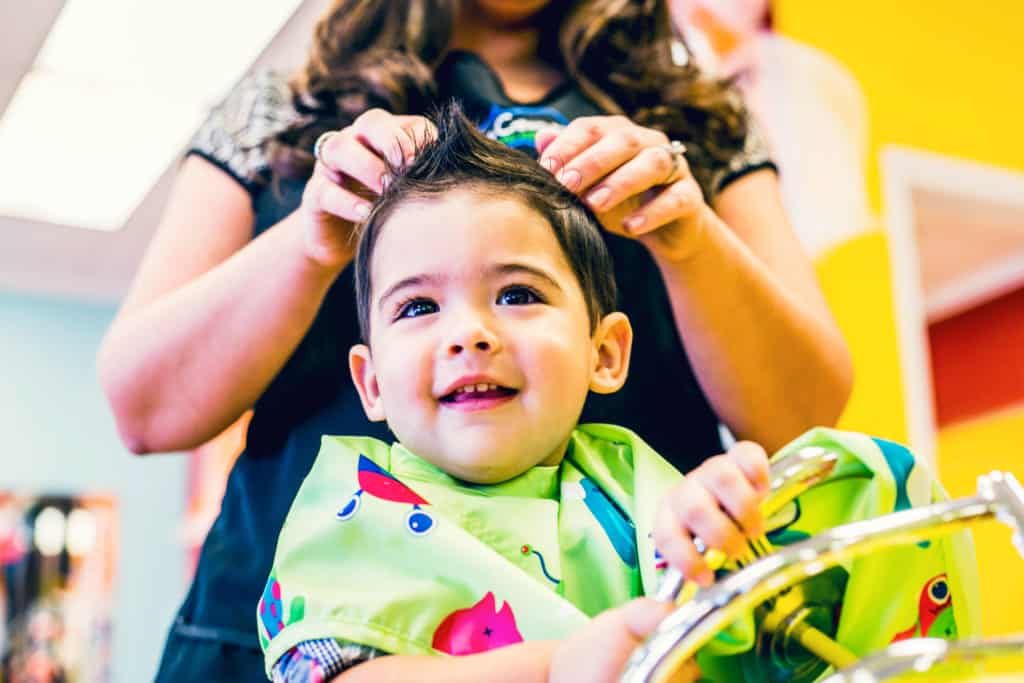 happy little boy at pigtails & crewcuts kids haircut franchise
