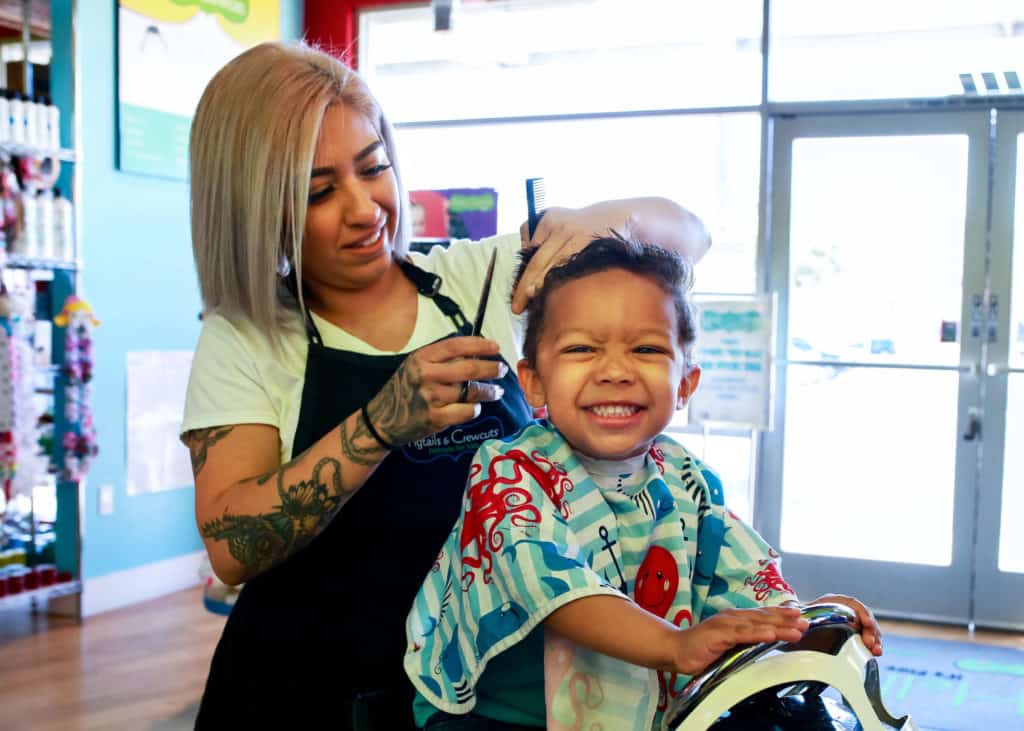happy boy getting haircut at pigtails & crewcuts