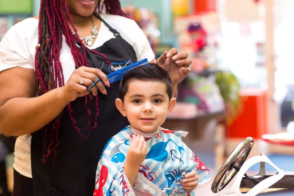 boy getting his hair cut at pigtails & crewcuts franchise