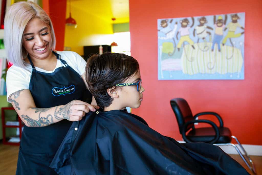 stylist cutting boy's hair in pigtails & crewcuts franchise